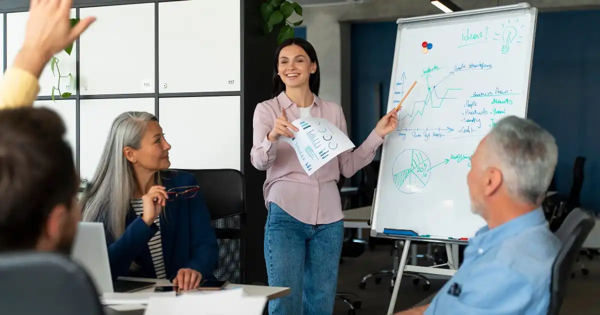 Woman presenting business data on a whiteboard to team members.